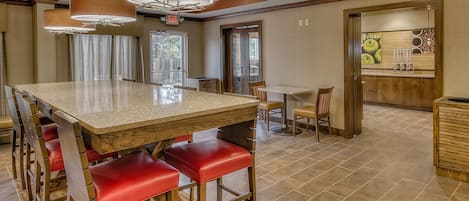 A spacious kitchen with a large island, red bar stools, and pendant lighting.