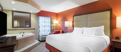 A hotel room with a large bed, a separate bathroom with a bathtub, a desk, and a television.