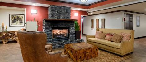 A living room with a stone fireplace, a brown leather armchair, a beige sofa, and a wooden coffee table.