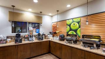 A self-service breakfast area with multiple food dispensers, a coffee machine, and a large poster advertising 'QUINTA'.