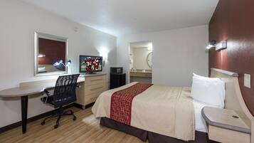 A hotel room with a bed, desk, chair, television, and a mirror.
