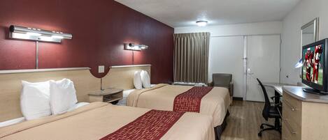 A hotel room with two beds, a desk, a chair, a television, and a window with curtains.