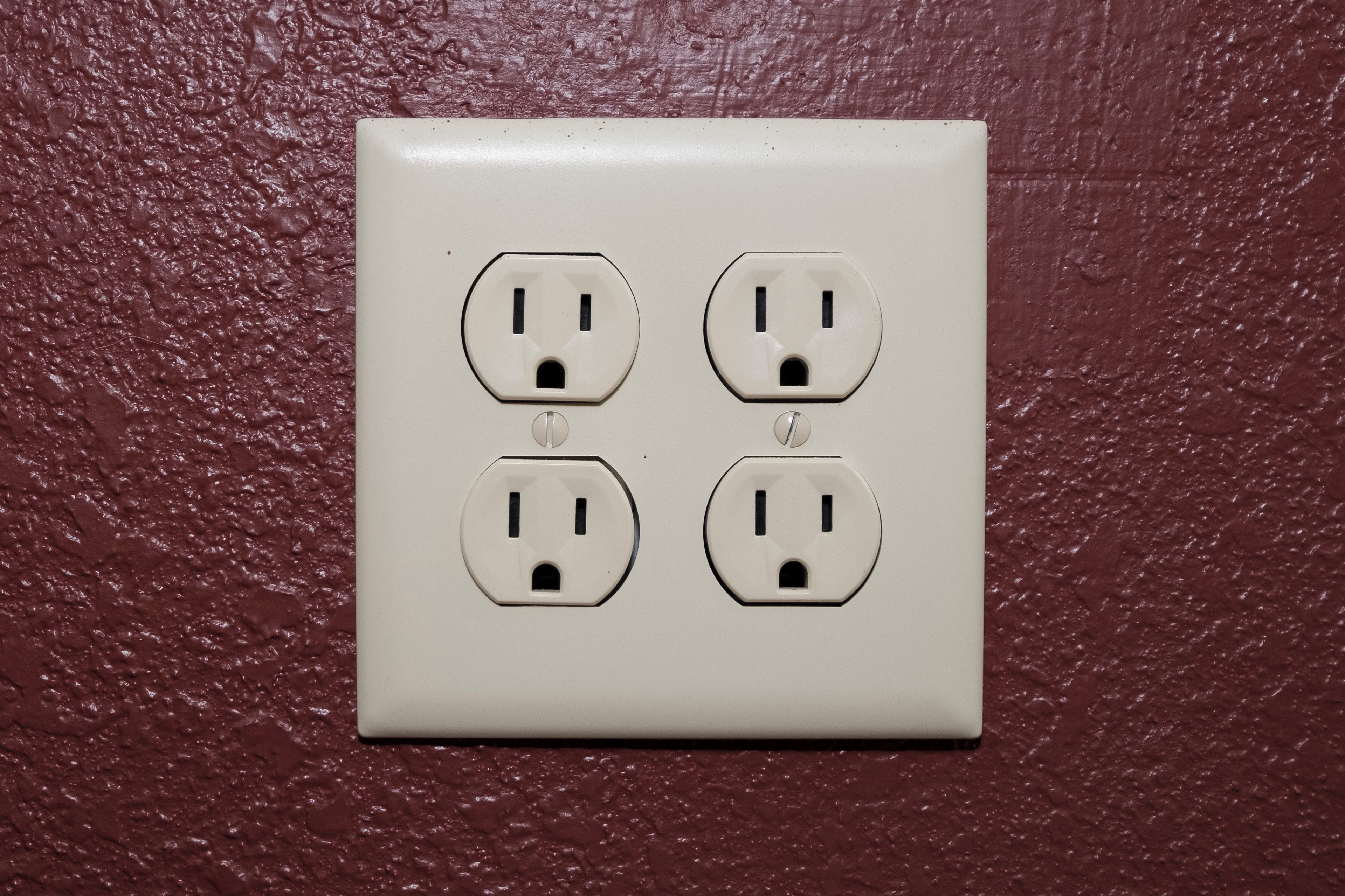 Un enchufe blanco con cuatro tomas en una pared con textura.