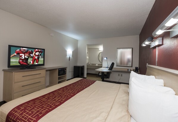 A hotel room with a bed, a television, a desk, and a mirror.