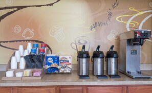 Un espace dédié au café, équipé de gobelets jetables, d’une machine à café et de différents types de crème pour café.