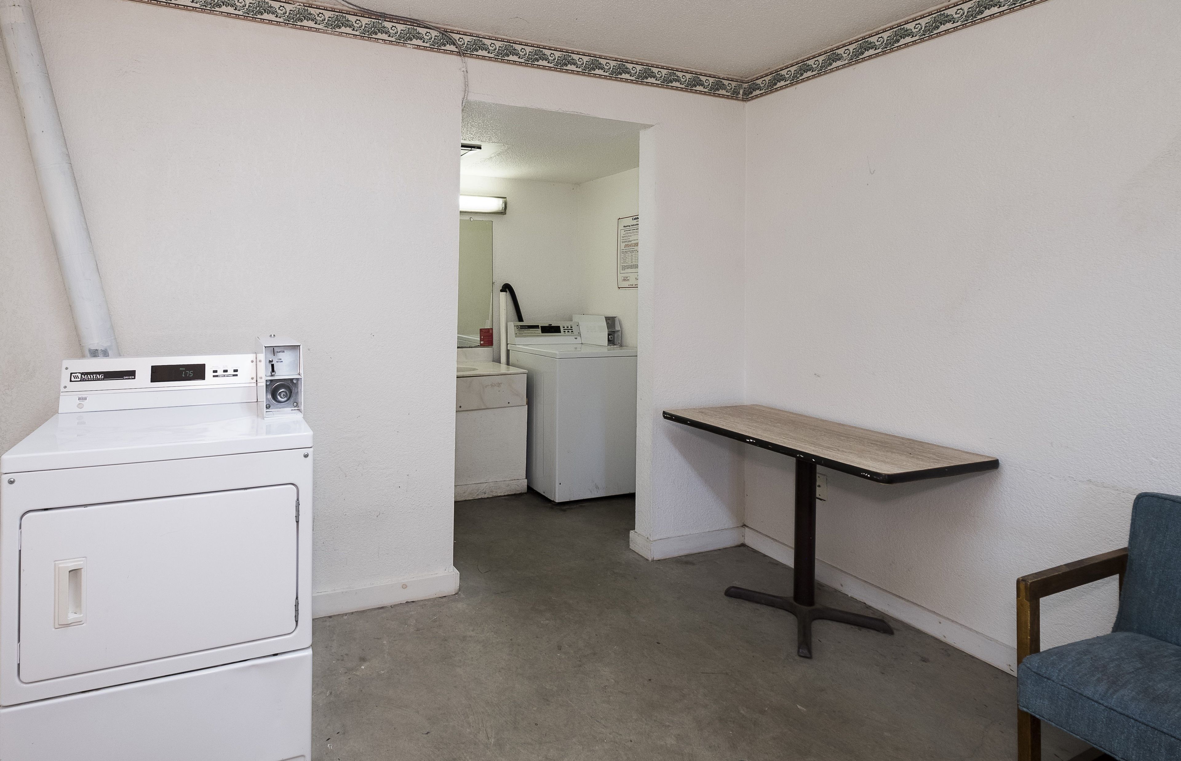 Une buanderie équipée d’un lave-linge, d’un sèche-linge et d’une table avec une chaise.