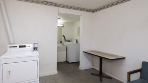 Un cuarto de lavandería con lavadora, secadora y una mesa con una silla.
