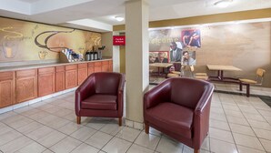 A hotel lobby with a reception desk, two leather chairs, a coffee machine, and a wall with a welcome sign. - Red Roof Inn Hagerstown - Williamsport, MD (Williamsport)