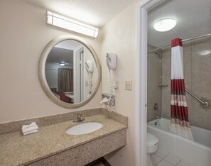 Ein Badezimmer mit Waschbecken, Spiegel, Haartrockner und Duschvorhang.