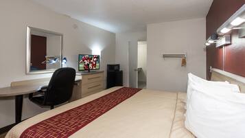 A hotel room with a bed, a desk, a television, and a mirror.