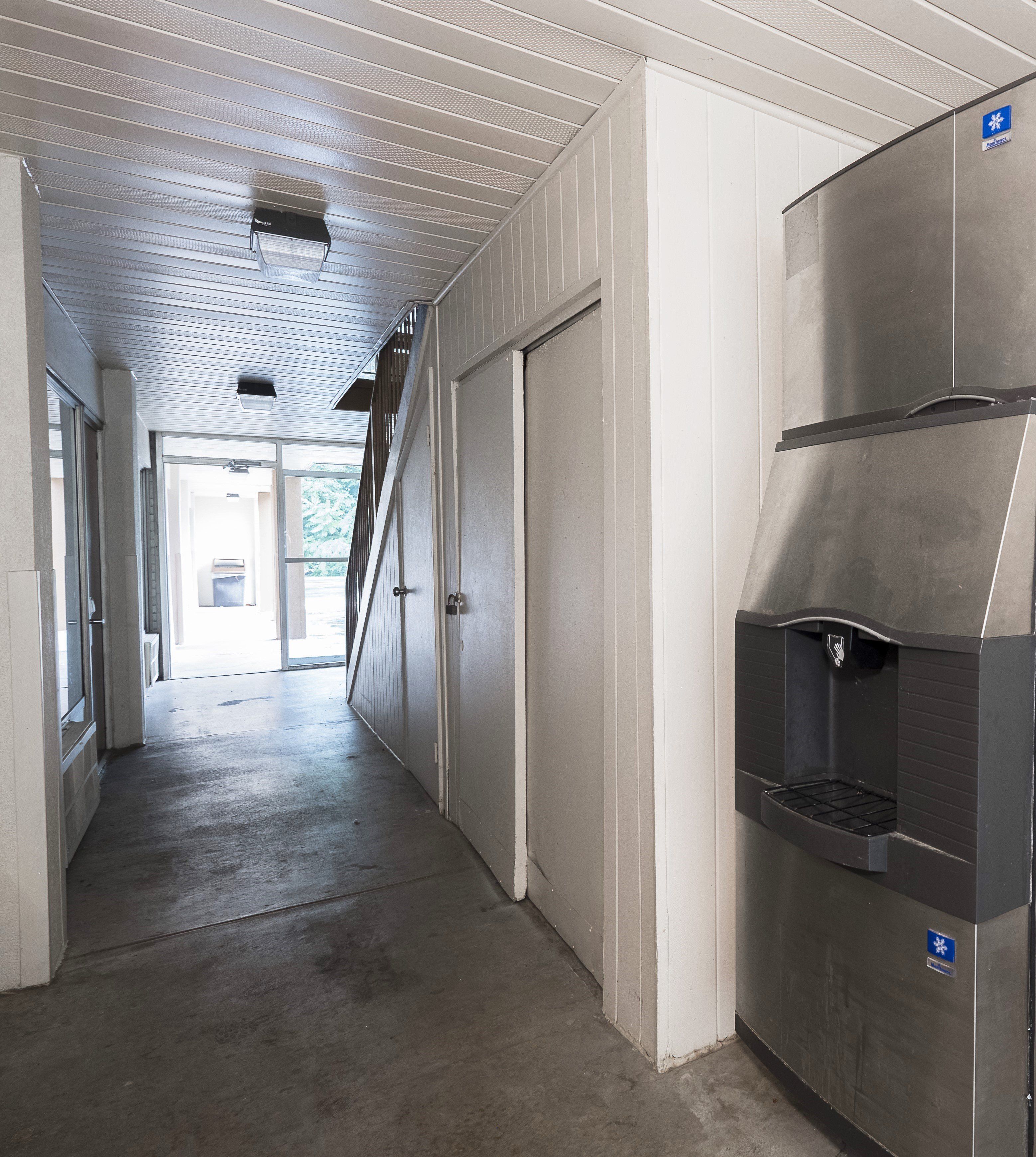 Un pasillo con un electrodoméstico de acero inoxidable, una puerta y un ventanal.