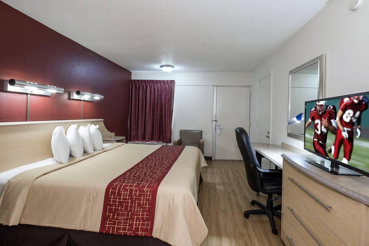 Ein Hotelzimmer mit Bett, Schreibtisch, Fernseher und einer Tür.