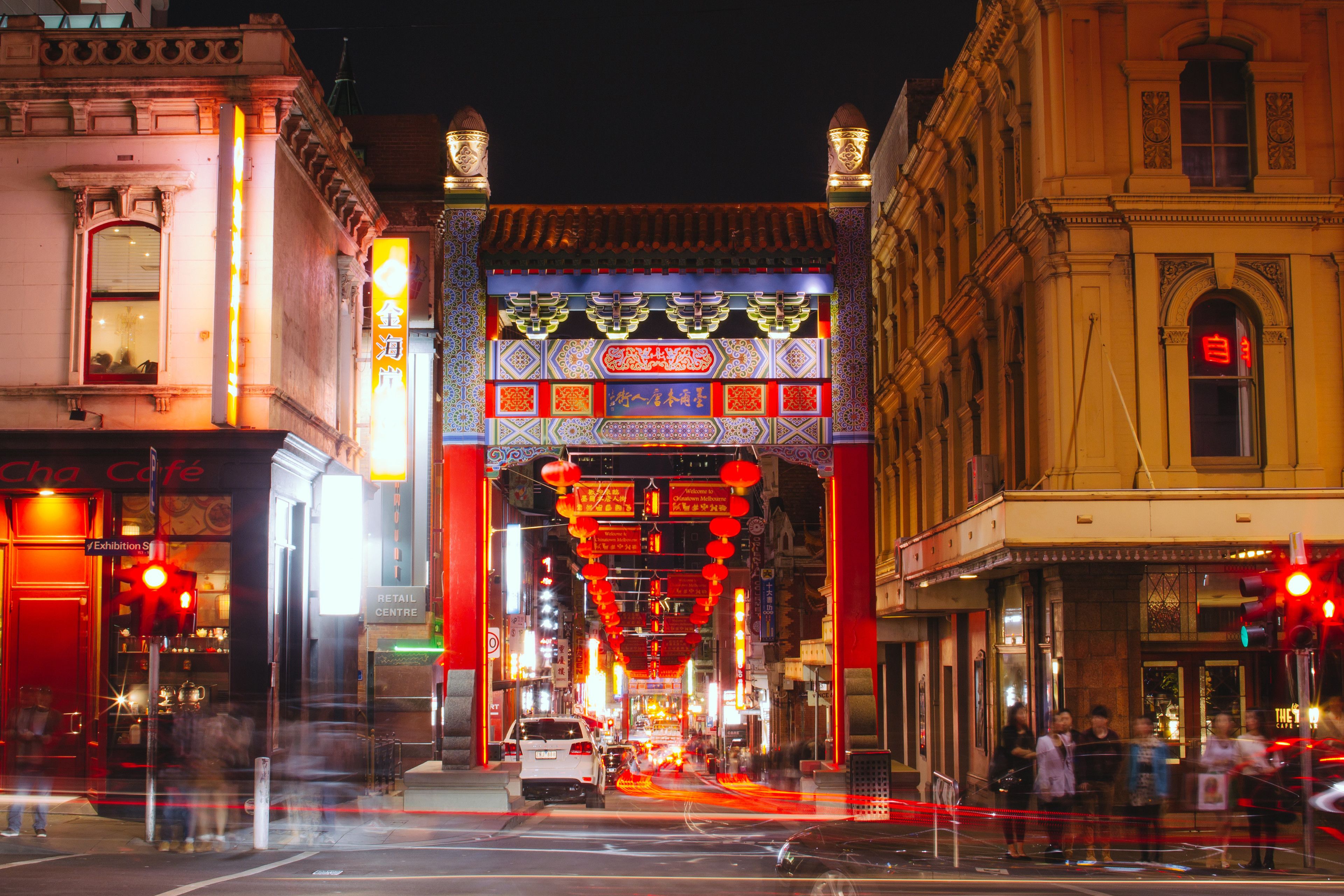 A street scene with traditional architecture, a pedestrian bridge, and illuminated signs.