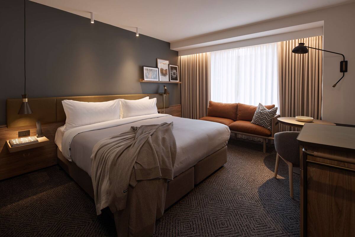 Ein modernes Hotelzimmer mit einem großen Bett, einer Couch, einem Schreibtisch und einer Lampe.