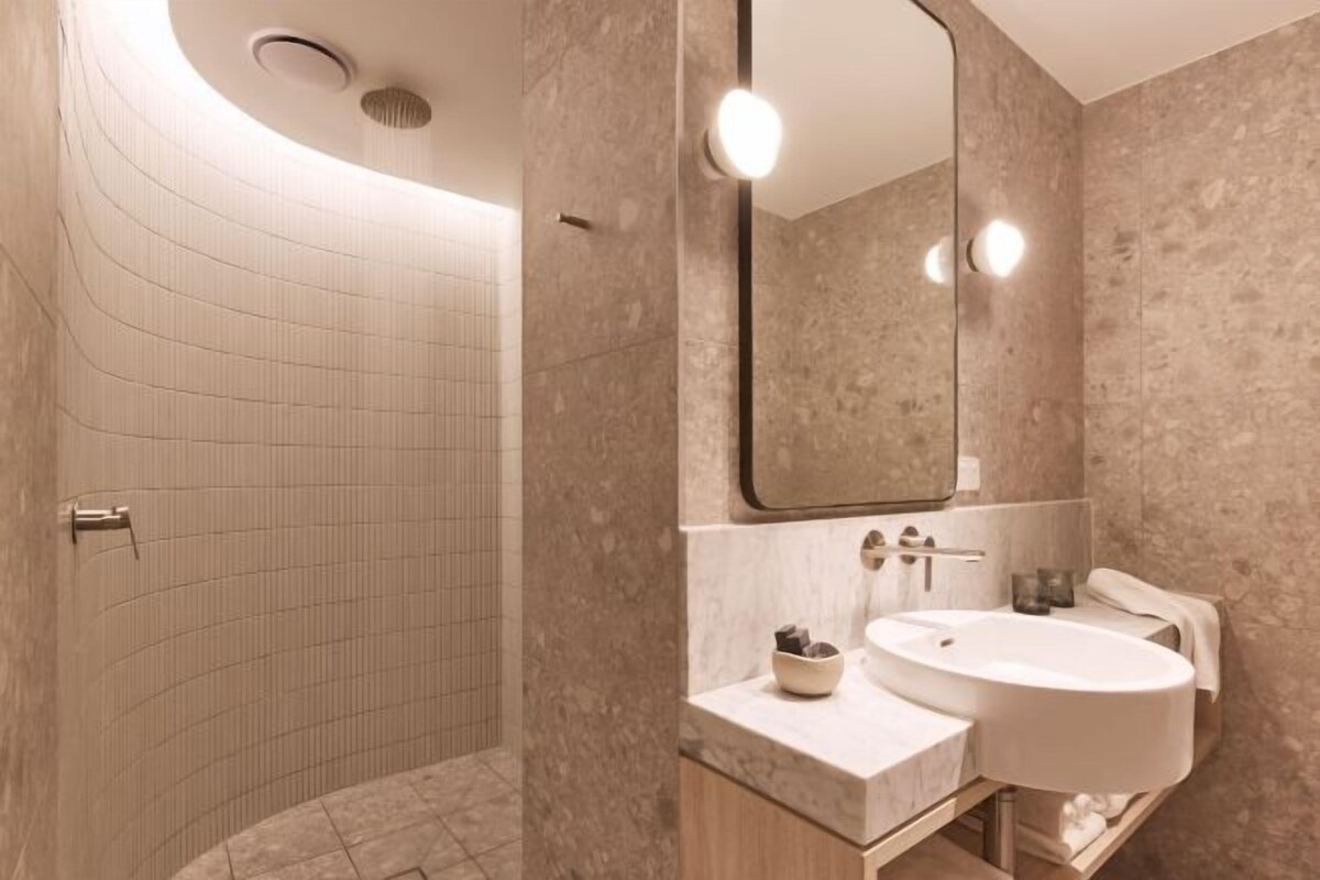 Un baño moderno con ducha de curvas, un espejo grande y un lavabo con encimera de mármol.