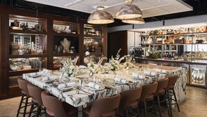 A spacious bar area with a marble-top bar counter, multiple stools, and a variety of bottles and glasses.