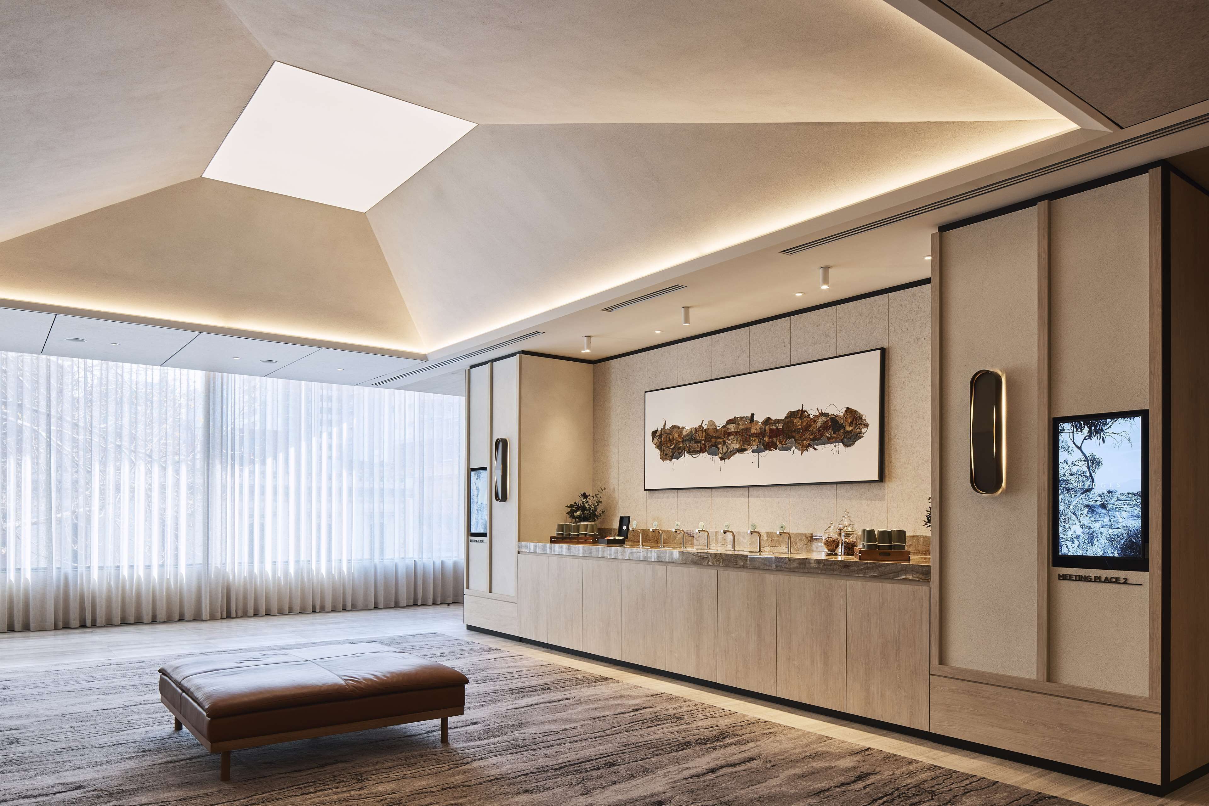 Une cuisine moderne dotée d’un grand îlot central, de luminaires suspendus et d’une grande fenêtre agrémentée de rideaux légers.