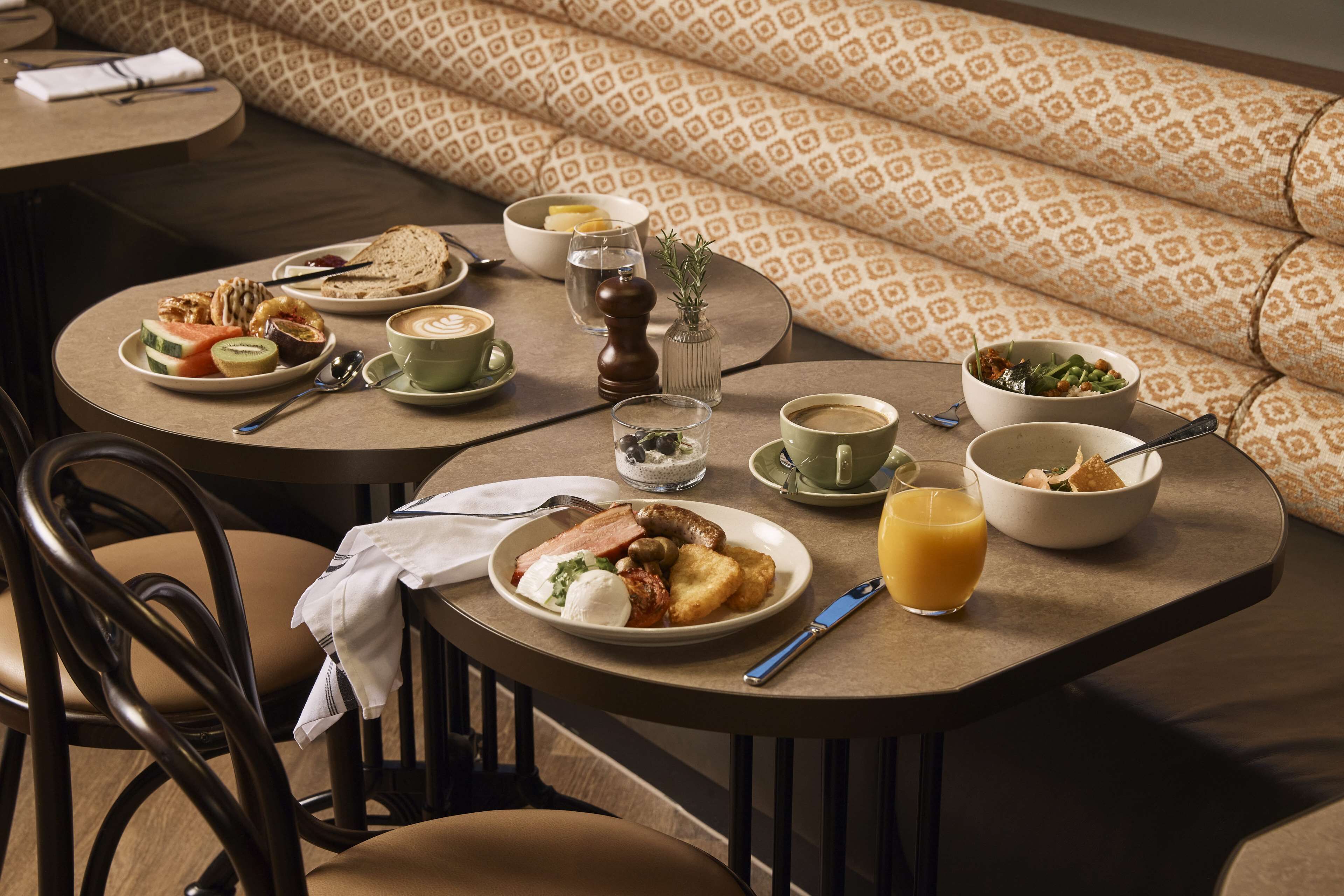 A breakfast setting with multiple tables, chairs, and a patterned sofa.