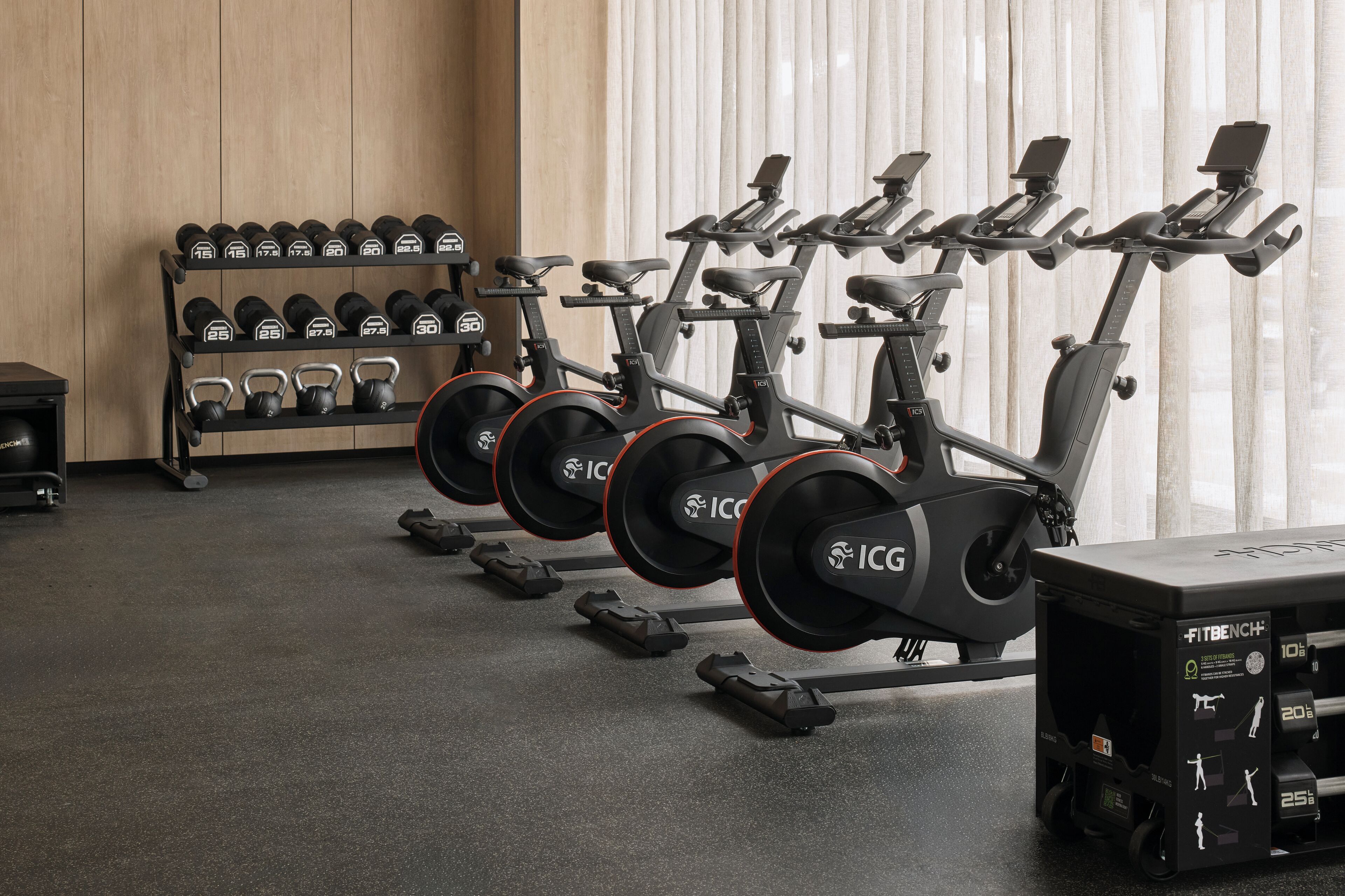 Un gimnasio con bicicletas estáticas, mancuernas y un banco.