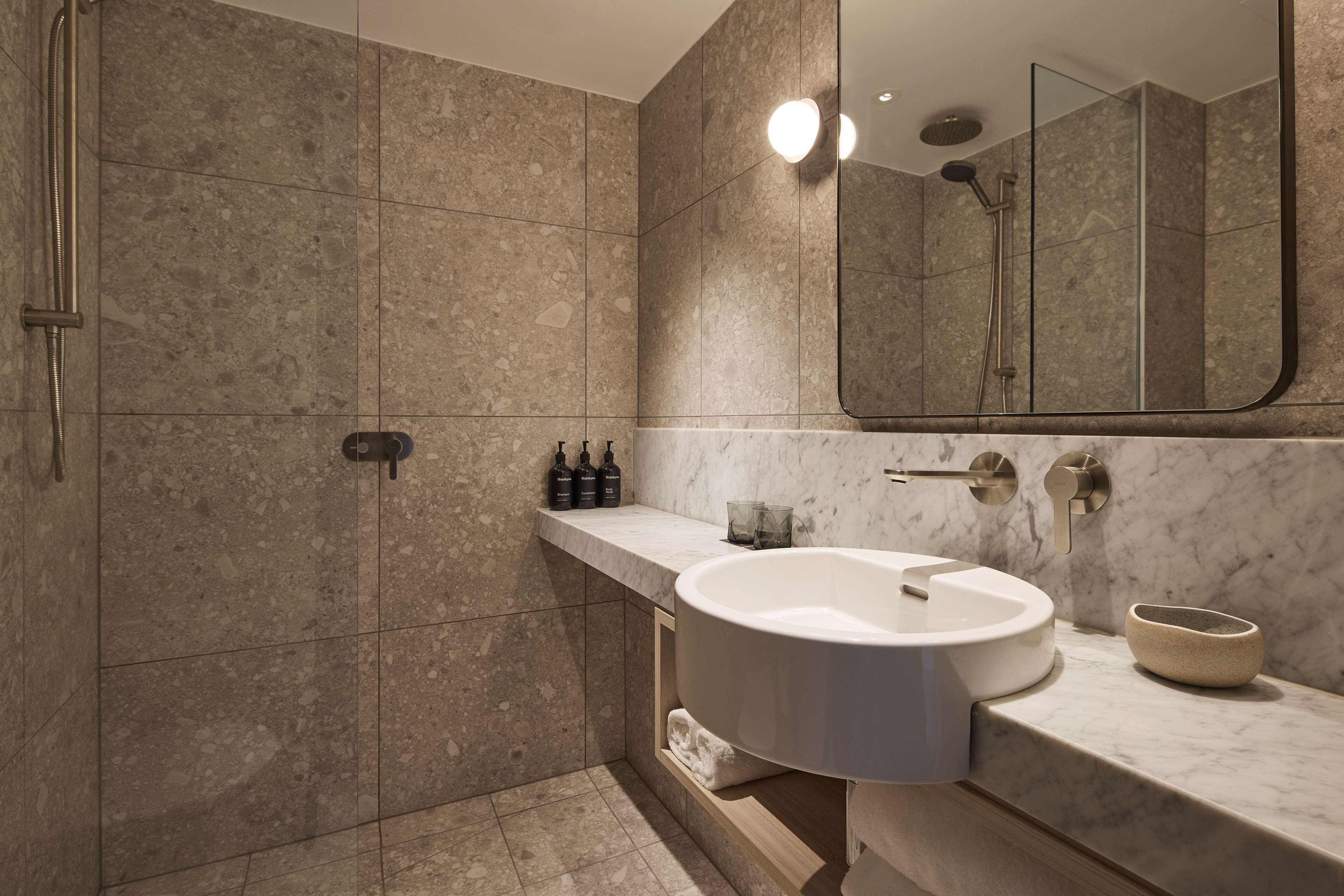 Een moderne badkamer met een grote wastafel, een douche en een spiegel.