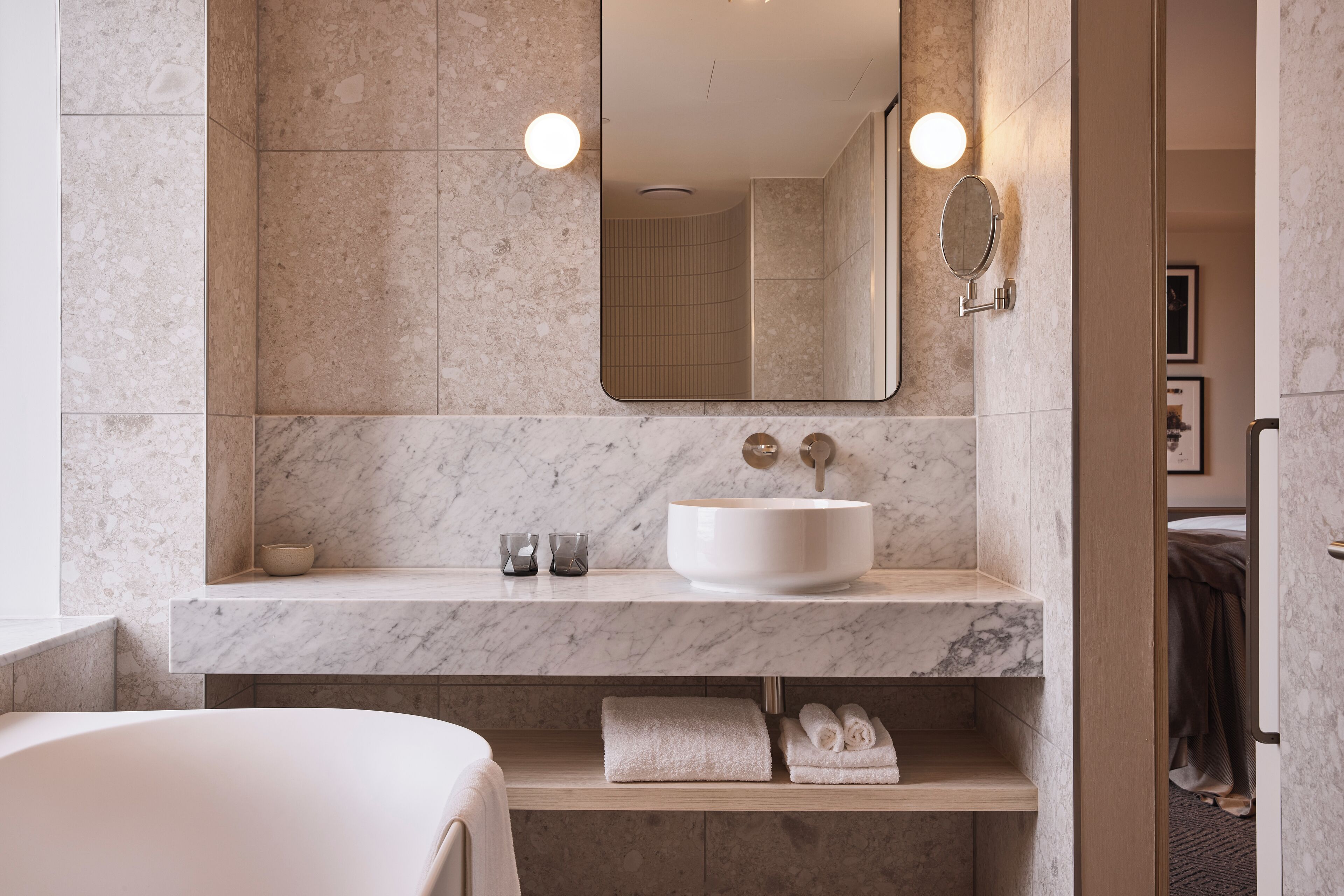 Un baño moderno con tocador de mármol, un espejo grande y una bañera.