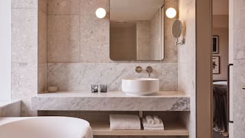 Un baño moderno con tocador de mármol, un espejo grande y una bañera.