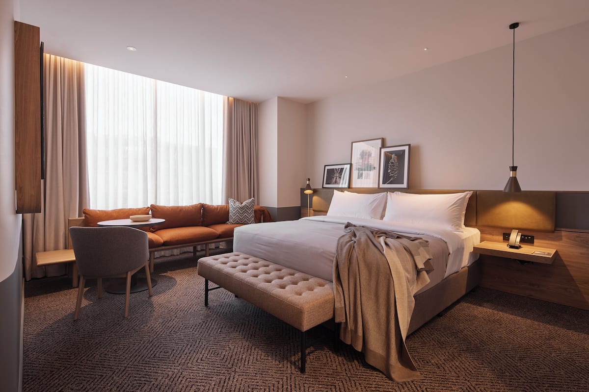Ein modernes Hotelzimmer mit einem großen Bett, einer Sitzecke, einem kleinen Tisch und einer Bank.