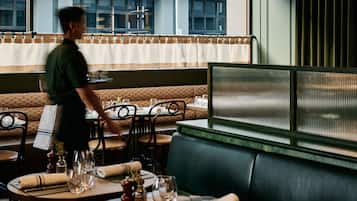 Un restaurante con cabinas, mesas y un camarero.
