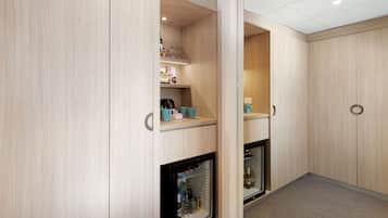 Una habitación compacta con estantes integrados, un refrigerador pequeño y una puerta con pomo redondeado.