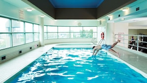 Una piscina con trampolín, un flotador salvavidas y un reloj en la pared.