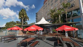 An outdoor patio area with red umbrellas, wooden tables, and benches.