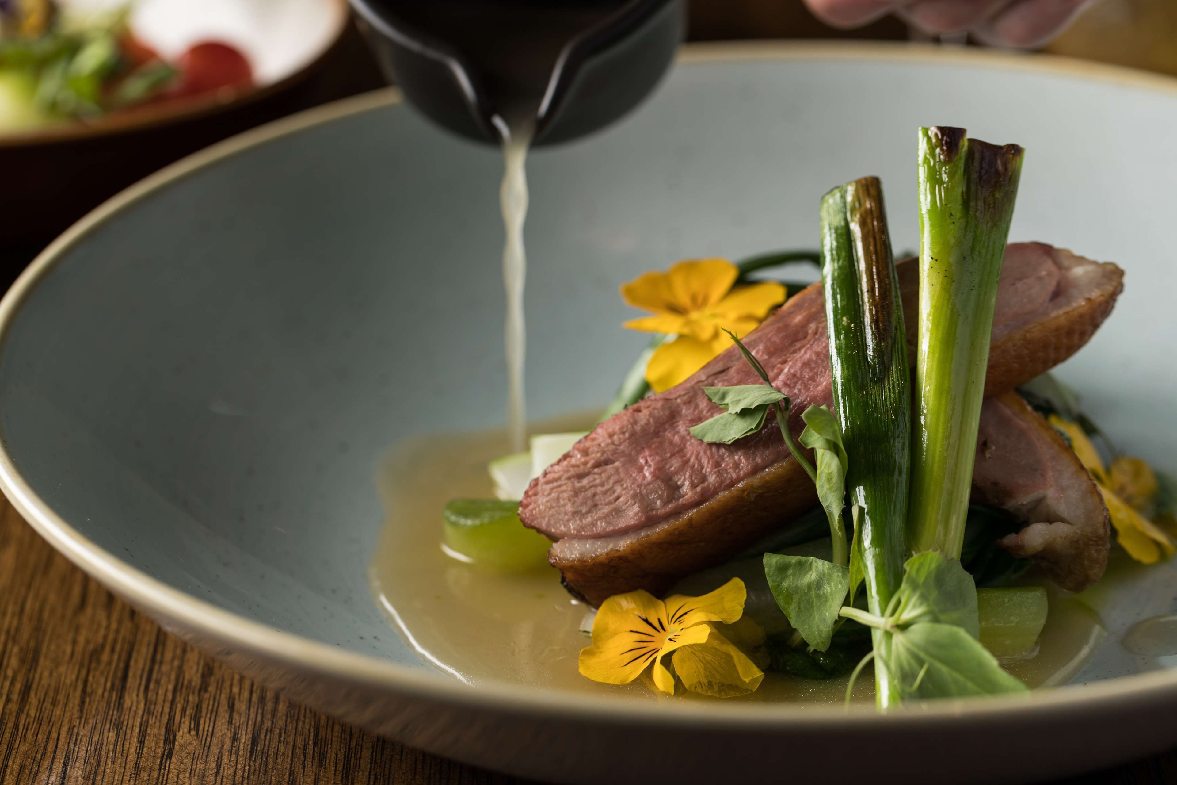 A plate of food with meat, vegetables, and a flower.