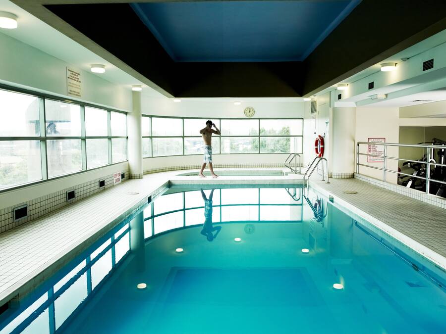 An indoor swimming pool with a tiled floor, a diving board, and a lifebuoy.