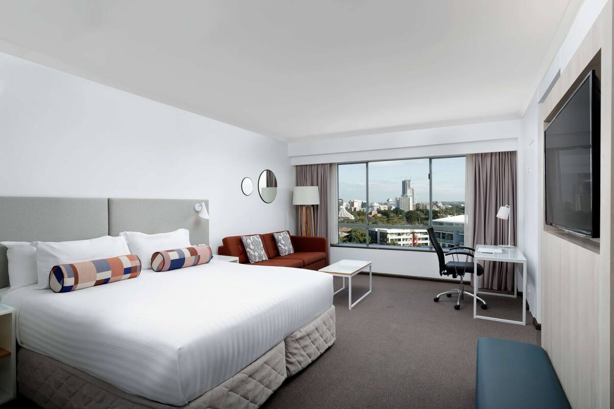 Una habitación de hotel con una cama grande, un sofá, un escritorio y un televisor.