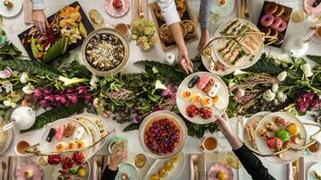 A table set for a meal with various dishes, including sandwiches, pastries, and fruit.