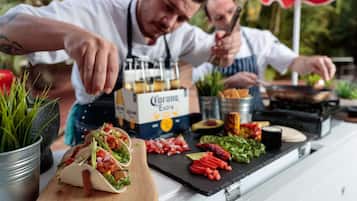 Un plan de travail de cuisine sur lequel on trouve une variété d’ingrédients et d’ustensiles de cuisine, notamment une boîte de bière Corona Extra, une planche à découper avec des légumes coupés et une planche à découper en bois sur laquelle se trouve un aliment emballé.