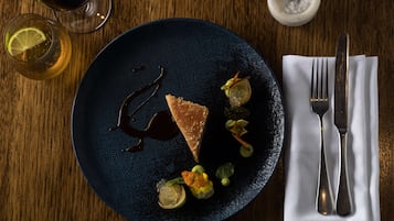 Un plato azul oscuro con una rebanada de pastel, adornos y un recipiente pequeño de azúcar.