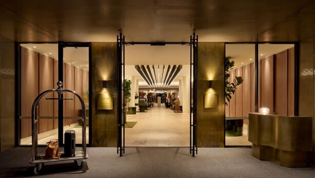 A hotel lobby with a reception desk, a luggage cart, and a long corridor leading to the rooms. - Sofitel Sydney Wentworth (Sydney)