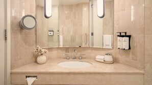 A modern bathroom with a large mirror, a sink, and a towel rack. - Sofitel Sydney Wentworth (Sydney)