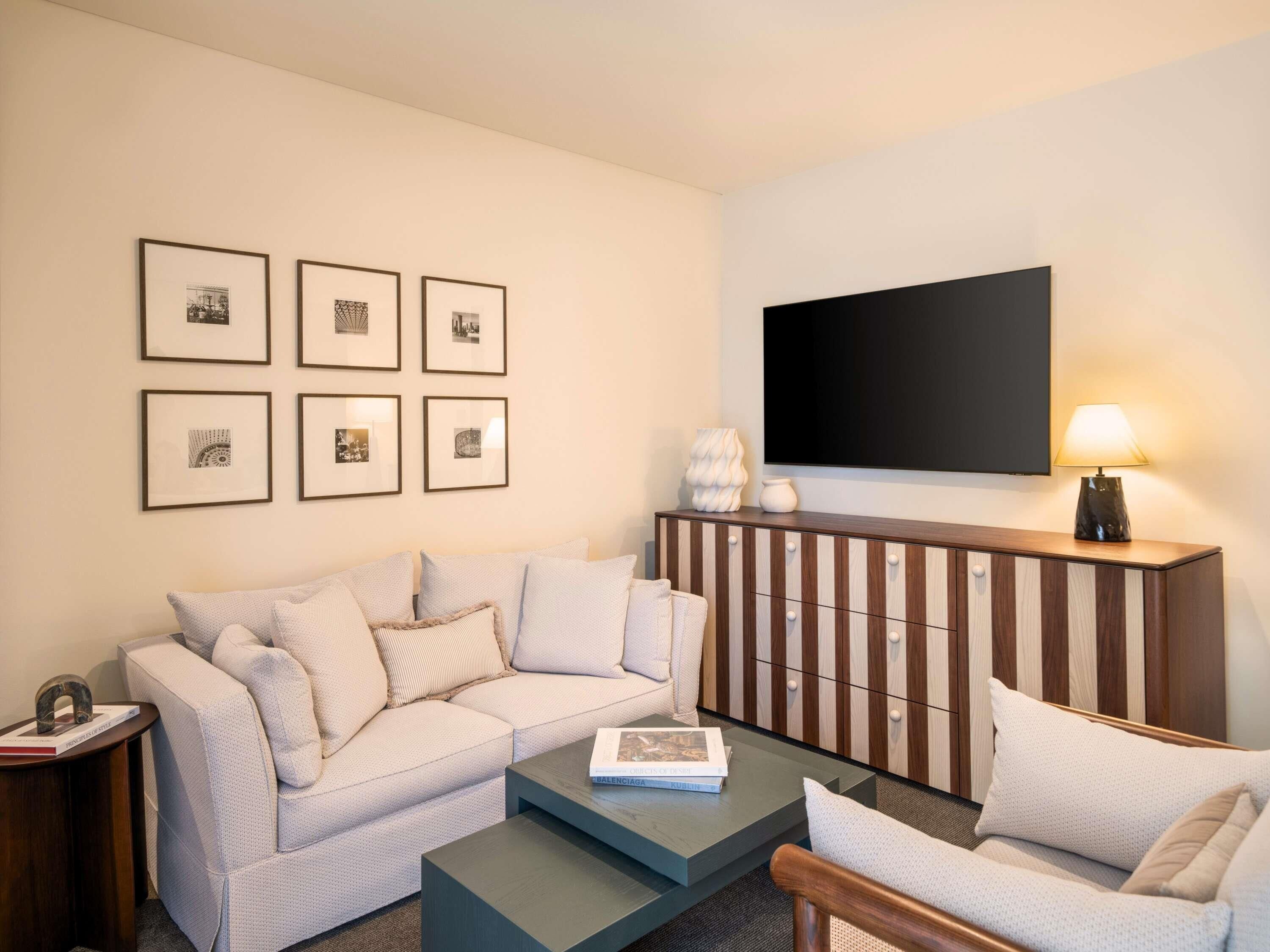 A modern living room with a sofa, a coffee table, a TV, and framed pictures on the wall.