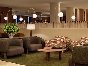A modern lounge area with sofas, a coffee table, and a vase of flowers. - Sofitel Sydney Wentworth (Sydney)