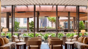 A spacious outdoor seating area with multiple sofas and chairs, large windows offering views of the city, and a covered section with a wooden ceiling. - Sofitel Sydney Wentworth (Sydney)