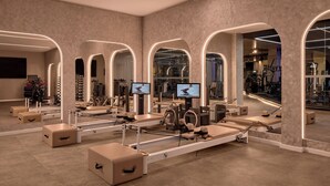 A modern gym with exercise equipment, mirrors, and a television screen. - Sofitel Sydney Wentworth (Sydney)