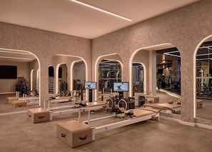 Academia moderna com equipamentos de ginástica, espelhos e uma tela de televisão.