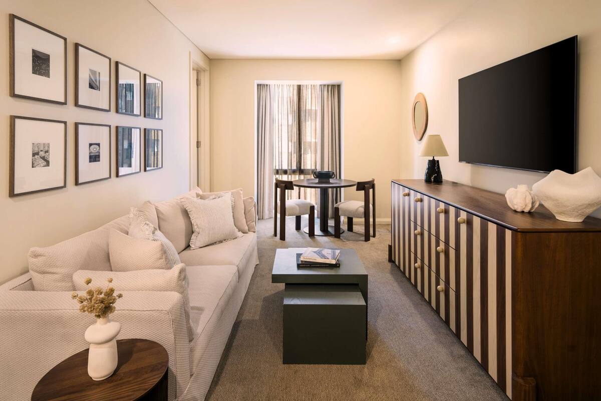 Ein modernes Wohnzimmer mit einer Couch, einem Couchtisch, einem Fernseher und gerahmten Bildern an der Wand.