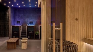 A modern spa area with wooden benches, a sauna, and a stone wall. - Sofitel Sydney Wentworth (Sydney)