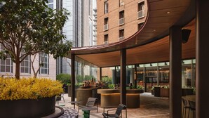 Un área de estar moderna al aire libre con techo curvo, un bar y vistas a un rascacielos.