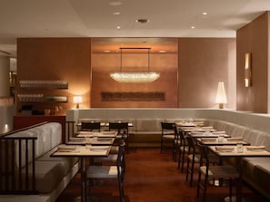 A modern restaurant with a central seating area, tables, and a chandelier. - Sofitel Sydney Wentworth (Sydney)