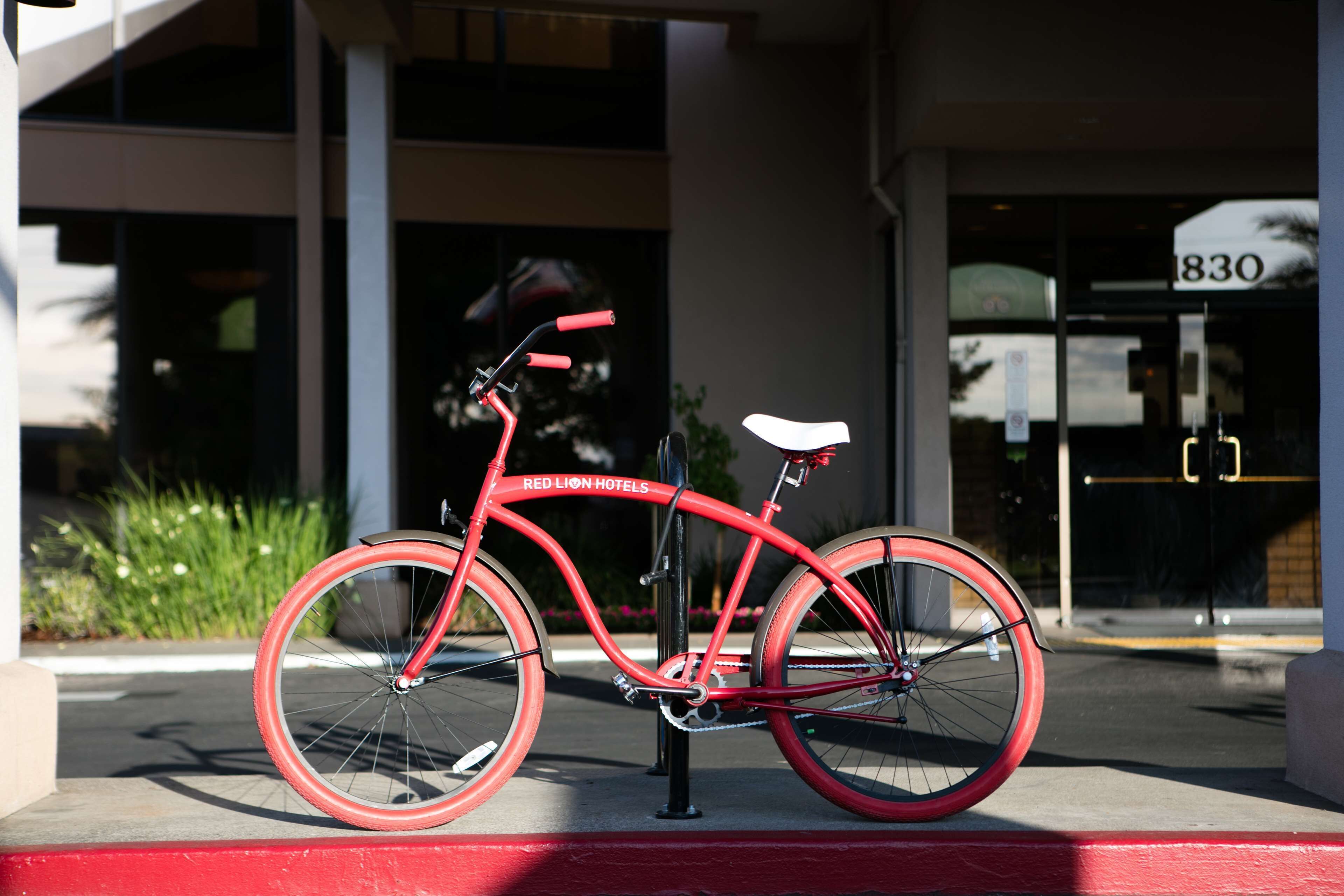 A red bicycle parked in front of a building with a sign reading "Red Lion Hotels".