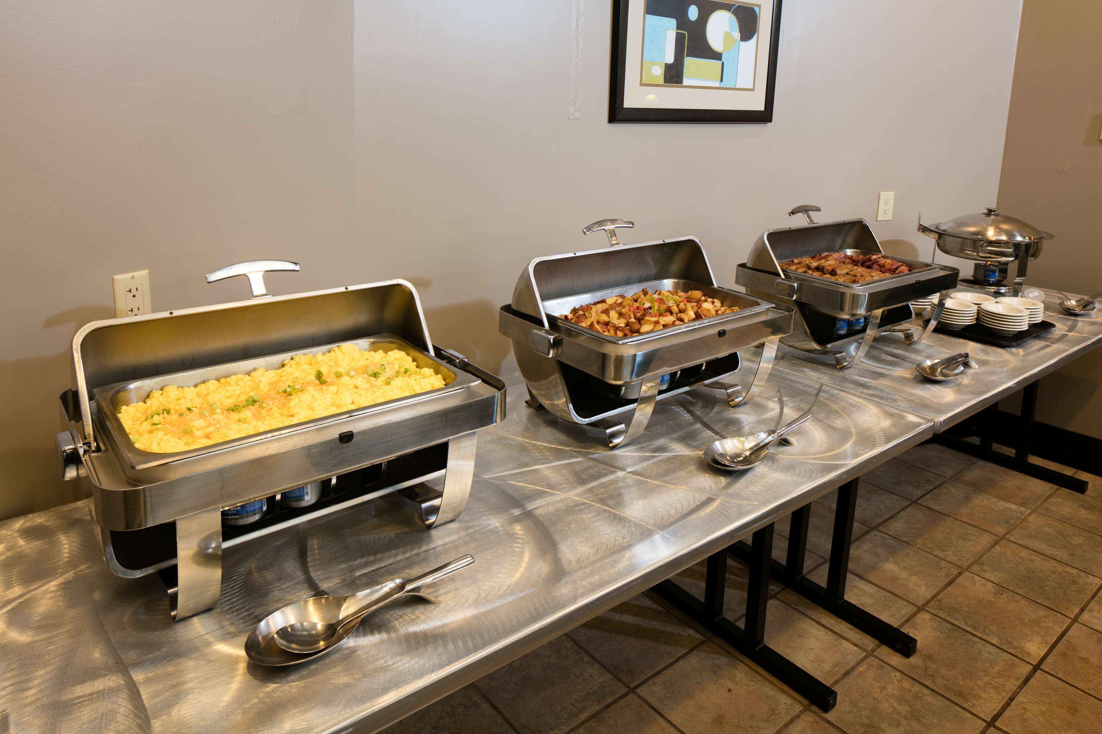 A buffet table with various food items and serving utensils.